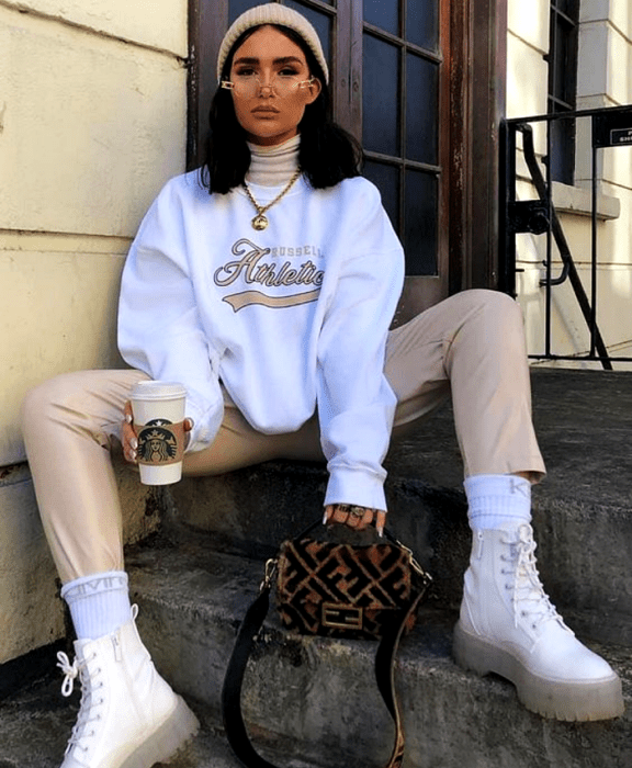chica de cabello castaño usando lentes, beanie gorro beige, sudadera blanca, pantalones beige, botines blancos de suela transparente y bolso café fendi