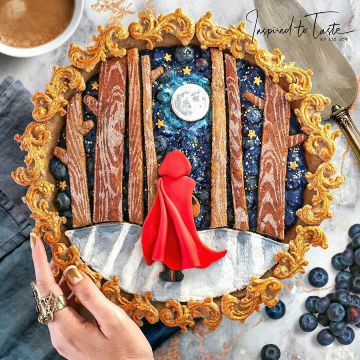 Pay decorado con Caperucita Roja, árboles y un cielo azul con luna llena