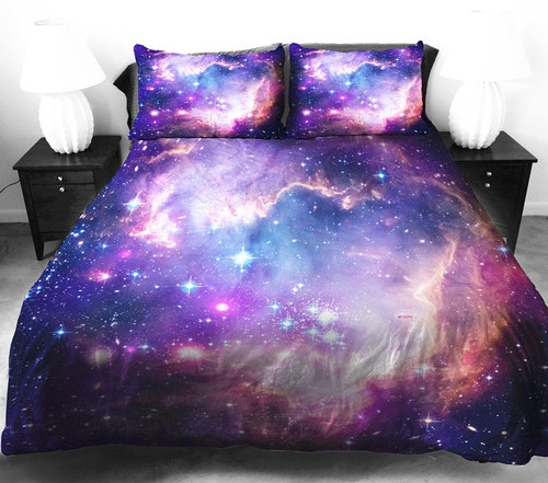 Cama matrimonial en habitación blanca con colcha de estampado de galaxia