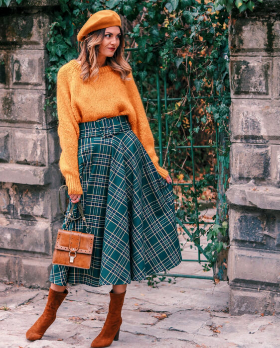 Look colorido aesthetic; mujer sonriendo con atuendo colorido, boina y suéter tejido anaranjados, falda larga con cuadros, bolsa café, botines de gamuza, cabello ombré