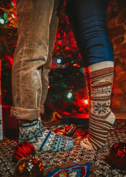 Piernas de hombre y de mujer con calcetas gruesas navideñas