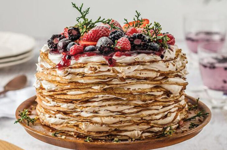 Pastel de Navidad de crepas rellenas de crema batida y decoradas con frutos rojos