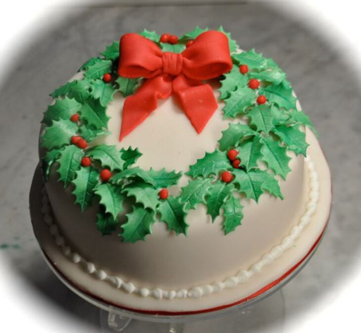 Pastel de Navidad de vainilla decorado con corona navideña y moño rojo