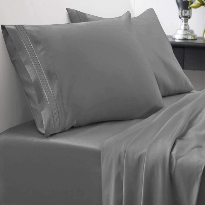 Cama con sábanas grises y almohadas