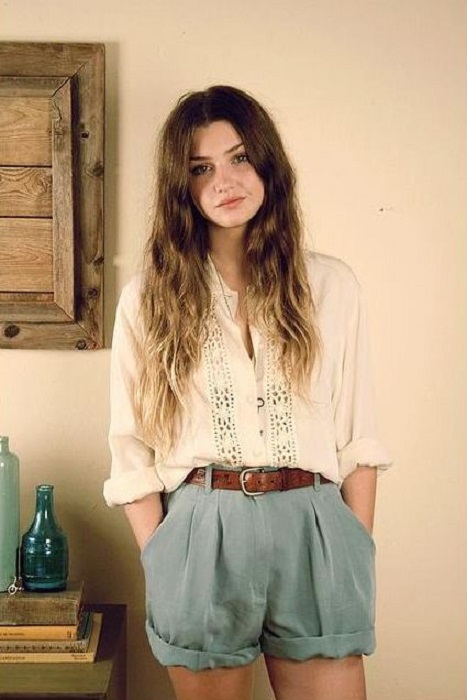 Chica usando shorts azul cielo, cinturón camel y blusa blanca suelta