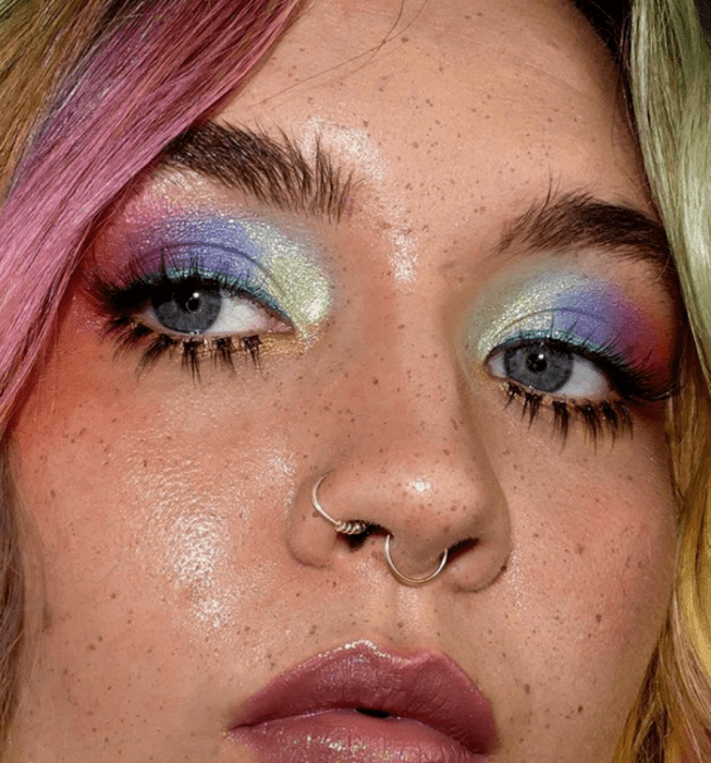 chica rubia usando sombras brillantes en azul, verde, rosa y morado
