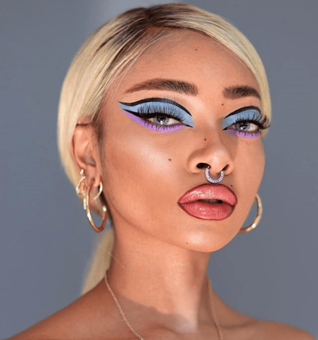 chica morena con cabello rubio usando sombras celestes y lila, delineador negro y pestañas postizas