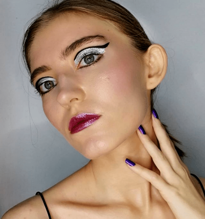 chica rubia con sombra plateada, delineado negro y labial brillante morado