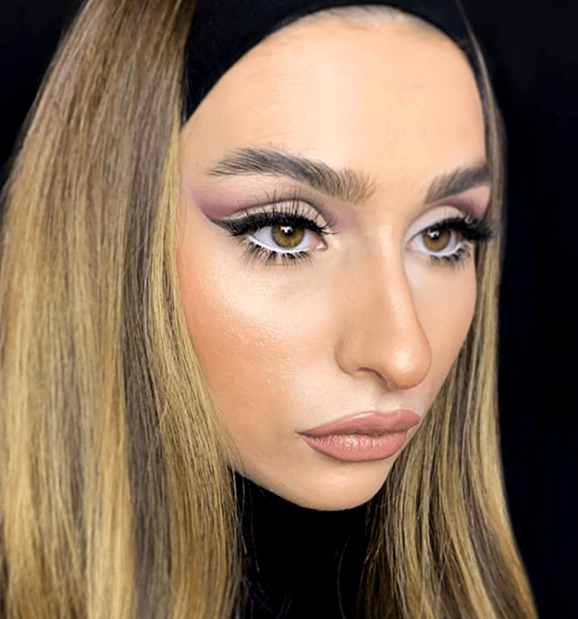 chica rubia usando un maquillaje con sombras lilas y delineado negro