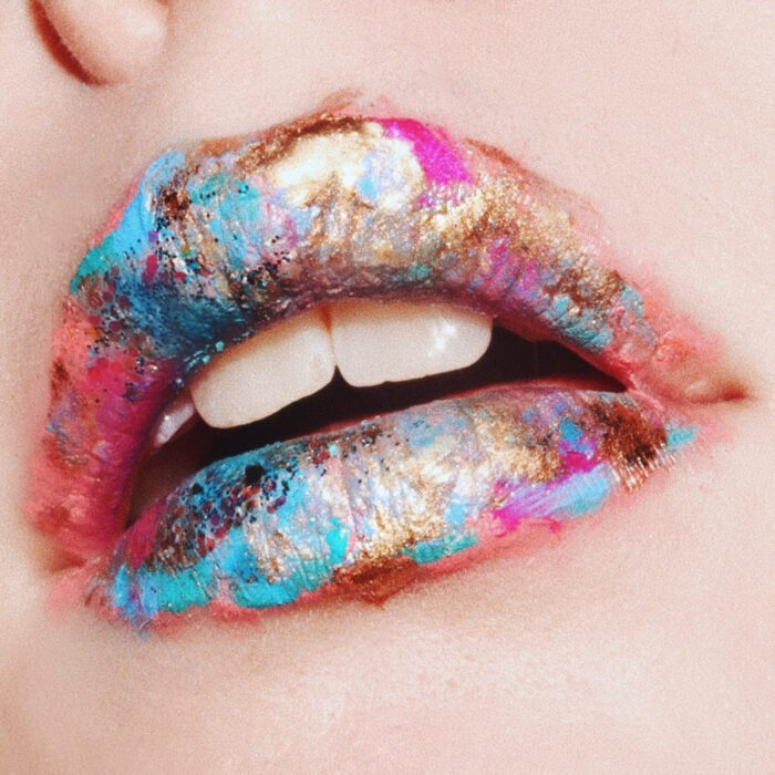 Maquillaje artístico de labios por maquilladora Tatiana Rose; bocado con labial azul, dorado y rosa con forma de pinceladas
