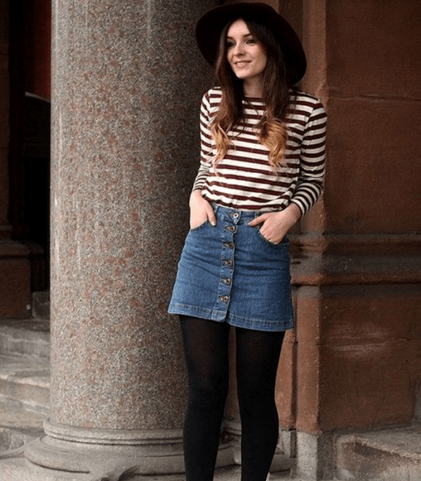 chica con sombrero, camiseta de rayas horizontales, minifalda de mezclilla, medias negras