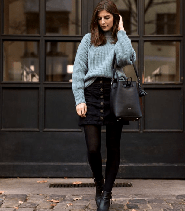 chica con suéter azul celeste, minifalda de mezclilla negra, medias negras