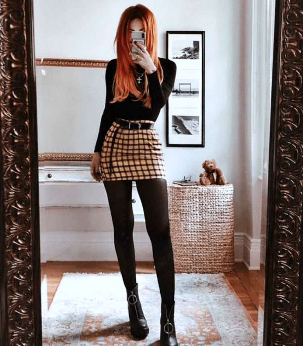 chica pelirroja con camisa de manga larga, minifalda amarilla con negro, medias negras y botines negros