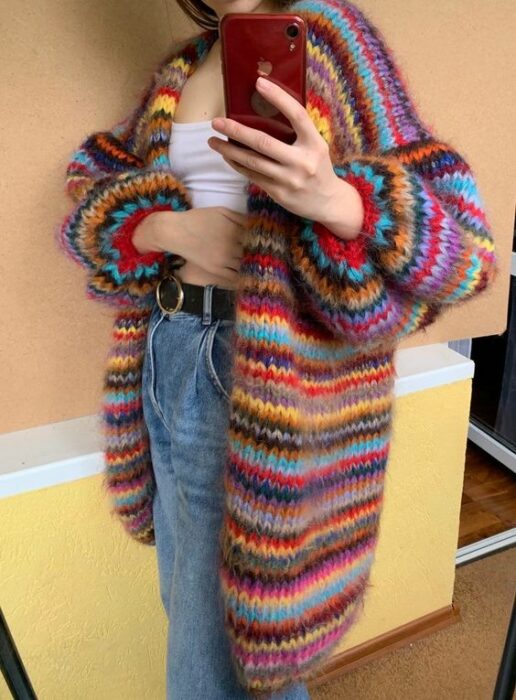 Chica usando cardigan largo de muchos colores, blusa blanca y jeans