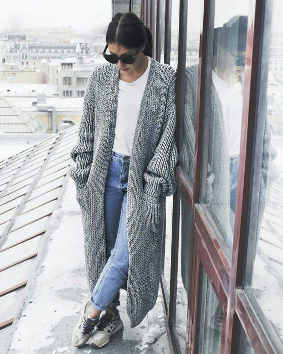 Chica usando cardigan largo color gris, blusa blanca y jeans