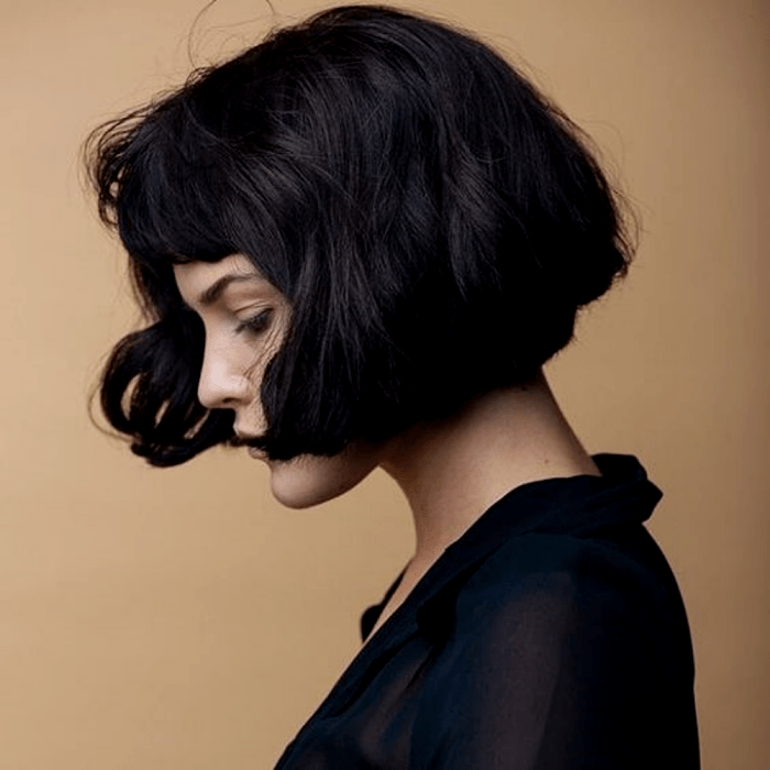 chica de cabello oscuro con corte estilo bob francés, french bob y blusa negra