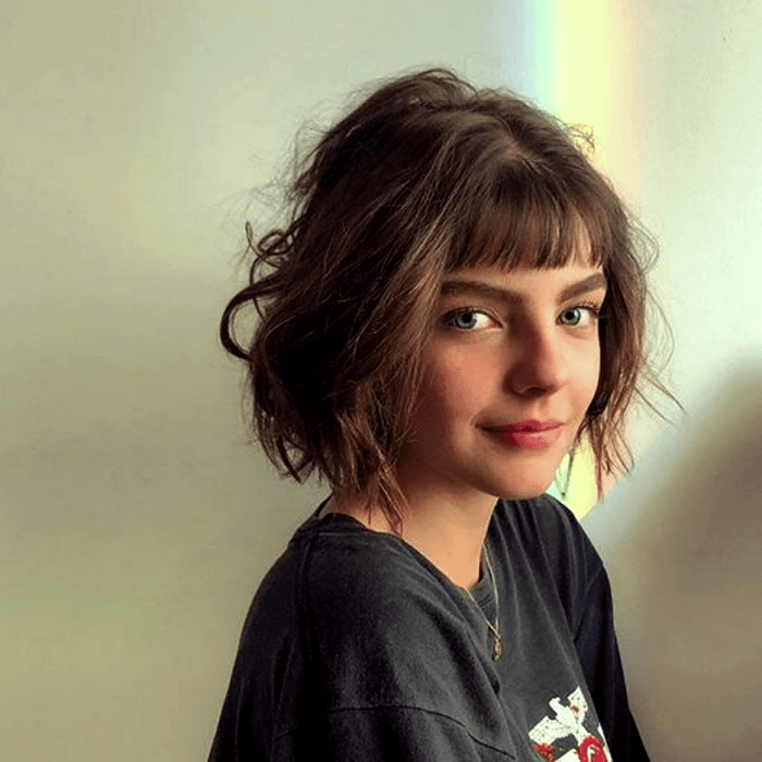 chica de cabello castaño con corte estilo bob francés, french bob y camiseta oversized negra con estampado