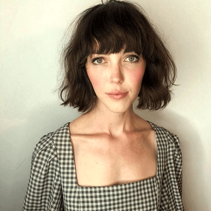 chica de cabello castaño con corte estilo french bob o bob francés, top blanco de cuadros con escote cuadrado