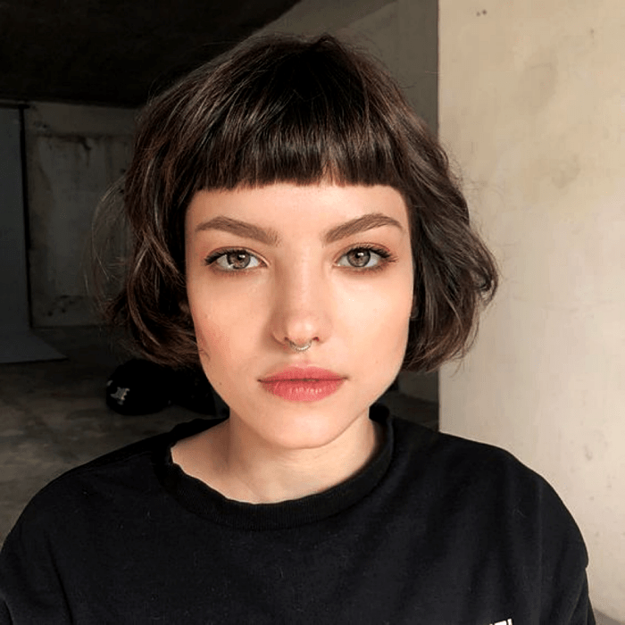 chica de cabello castaño usando un corte de cabello estilo french bob, bob francés, con camiseta negra
