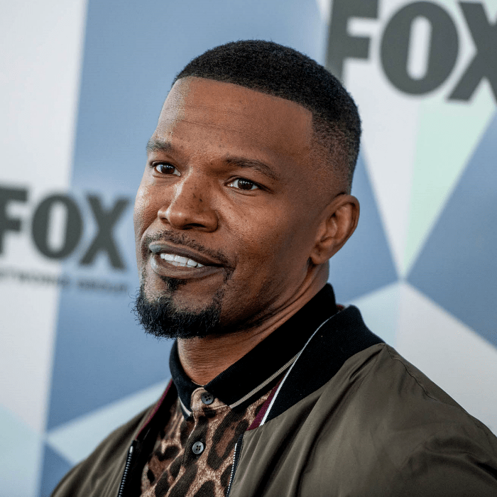 jamie foxx usando una camisa polo de animal print con cuello negro y chamarra tipo bomber jacket verde militar con cuello negro