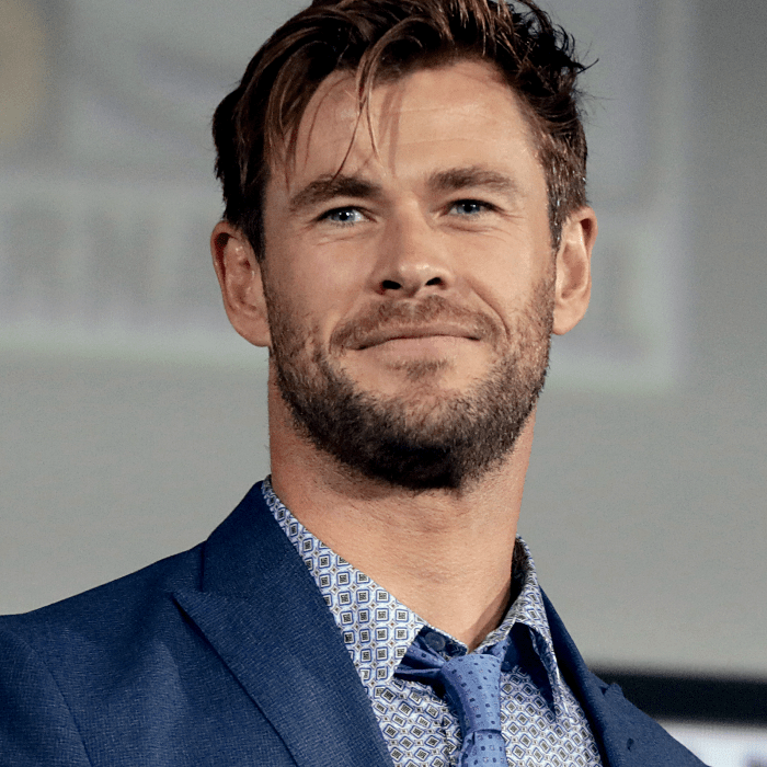 chris hemsworth usando una corbata azul con lunares, camisa de vestir azul claro con cuadros, saco de vestir azul