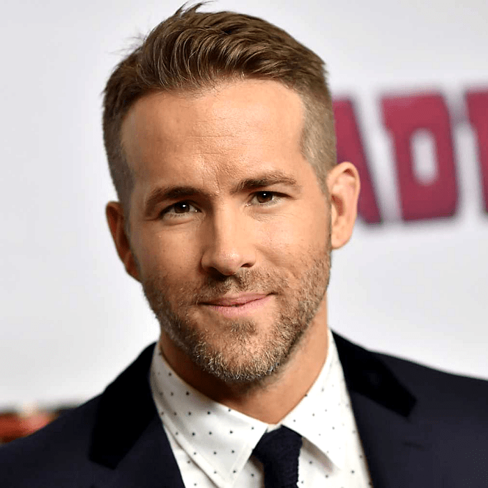 ryan reynolds usando una camisa de vestir blanca con lunares negros, corbata negra y saco negro