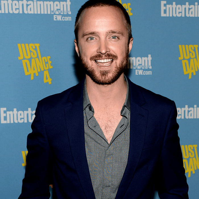 aaron paul usando una camisa gris de vestir y un saco azul