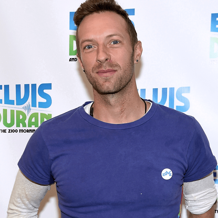 chris martin usando una camiseta azul claro de manga corta y una camiseta blanca de manga larga blanca