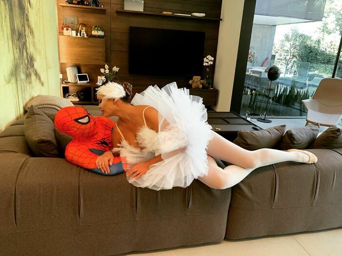 Chrissy Teigen y John Legend acostados en un sillón disfrazados como Spiderman y el cisne blanco