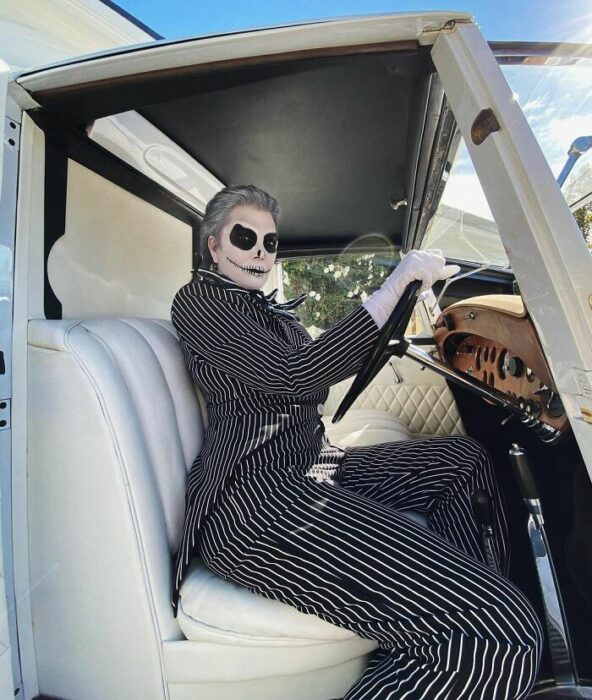 Kris Jenner posando en un automóvil blanco al volante disfrazada como Jack skellington