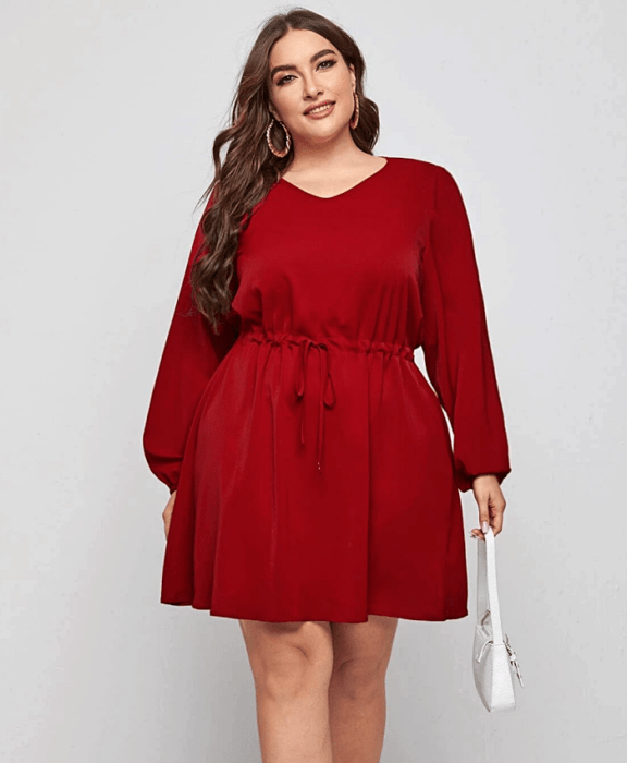 chica curvy usando un vestido rojo de cuello redondo, mangas largas, ajuste a la cintura y bolso de mano blanco