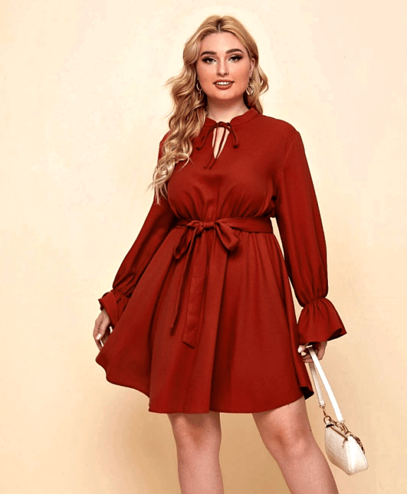 chica rubia usando un vestido rojo de manga larga, cuello alto, ajuste a la cintura y bolso blanco de mano