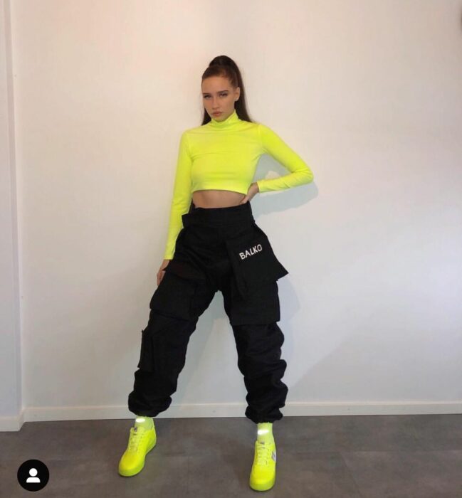 Chica usando un outfit de pantalón negro con una blusa de color verde limón