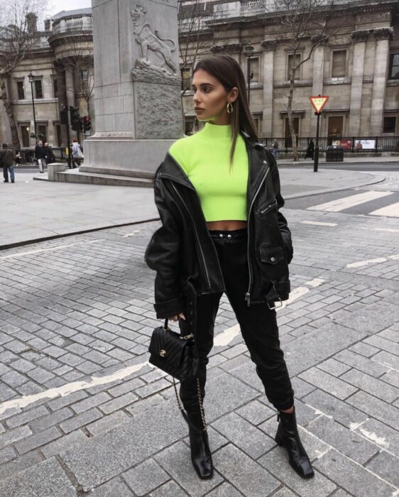 Chica usando un outfit negro con una blusa de color neón