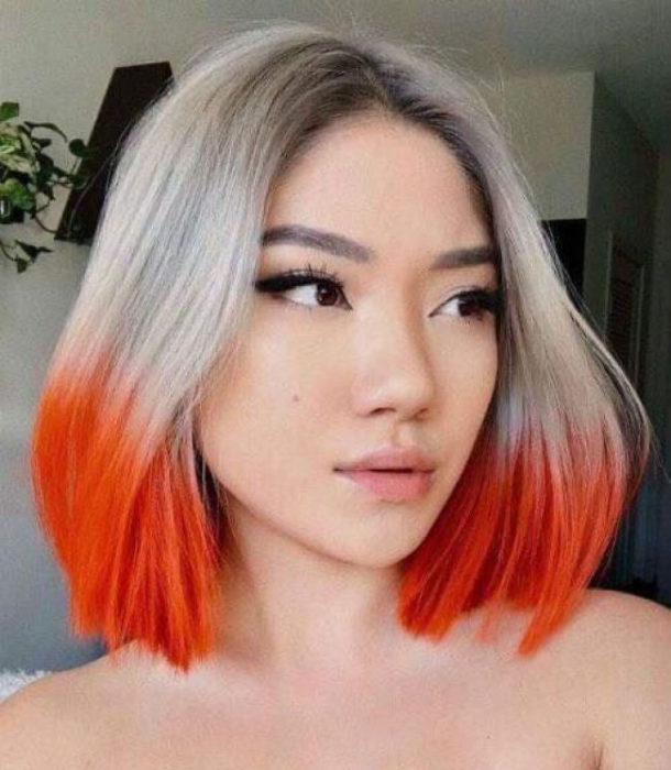 Chica con el cabello teñido en platinado con puntas naranjas