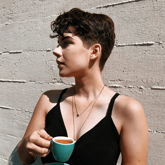 chica de cabello pixie super corto con un poco de volumen al frente, top negro de tirantes negros con cuello en V
