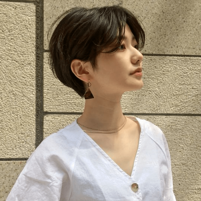 chica con corte de cabello estilo pixie con capas, top blanco en cuello en V