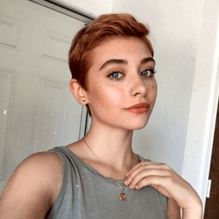 chica pelirroja con corte de cabello pixie estilo de los 60, top de tirantes gris