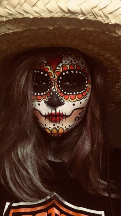 Chica con maquillaje de Catrina en colores naranja y blanco