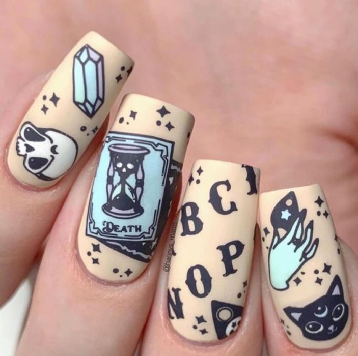 Manicura inspirada en noche de brujas de fondo beige con detalles en negro y azul cielo