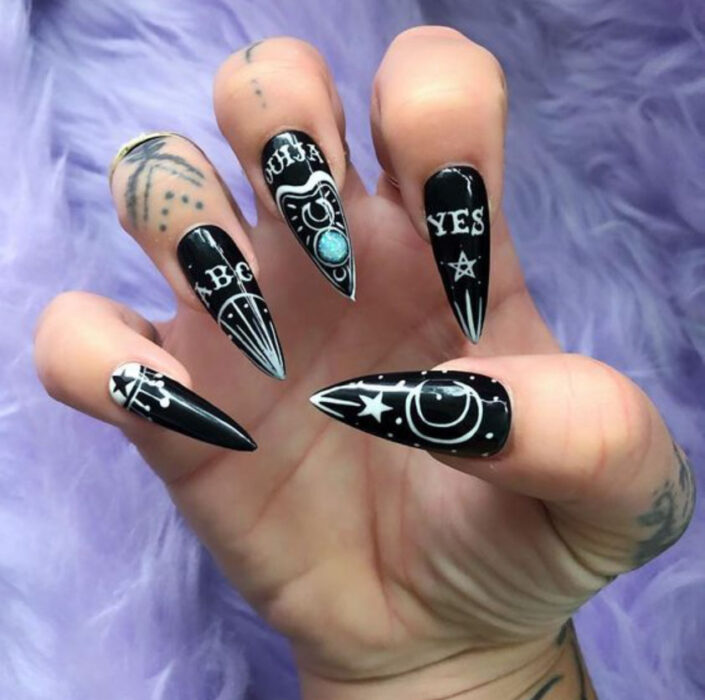 Manicura inspirada en noche de brujas de color negro con detalles en blanco