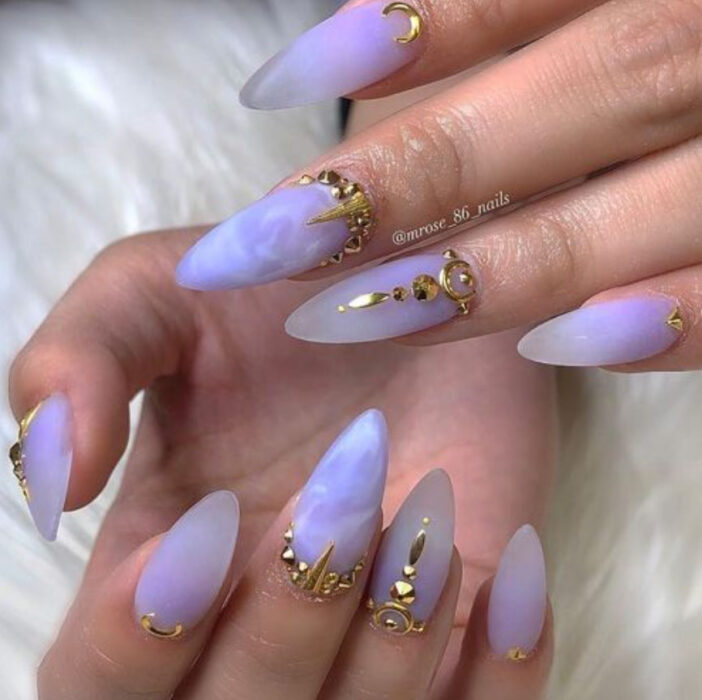 Manicura inspirada en noche de brujas de color lila con aplicaciones doradas