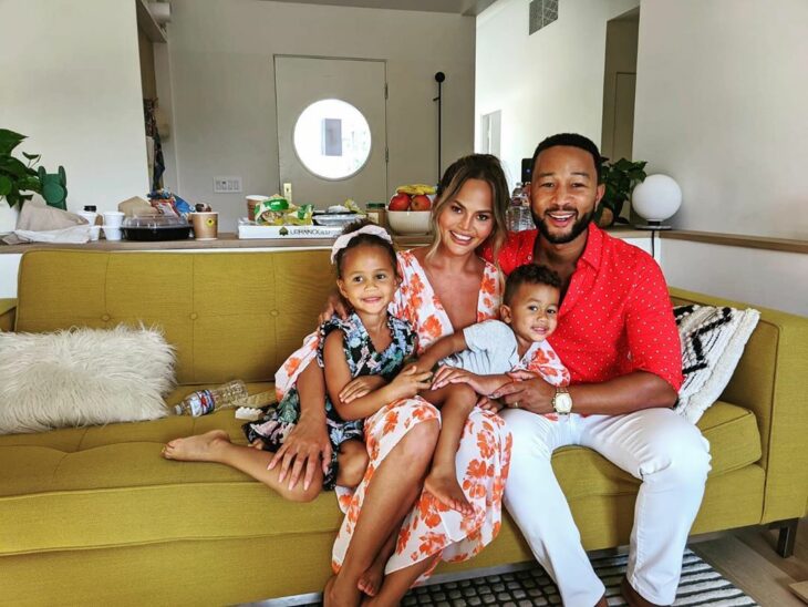 Chrissy Teigen y John Legend posando para una foto mientras están junto a sus hijos