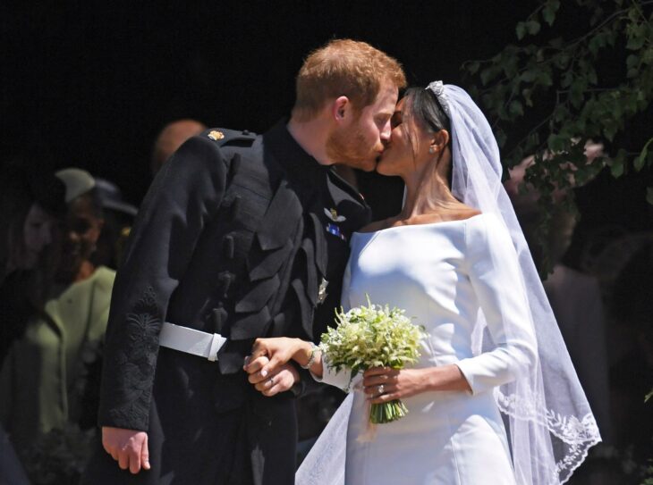 Meghan Markle el día de su boda luciendo un vestido blanco de encaje con un ramo de novia con flores blancas 