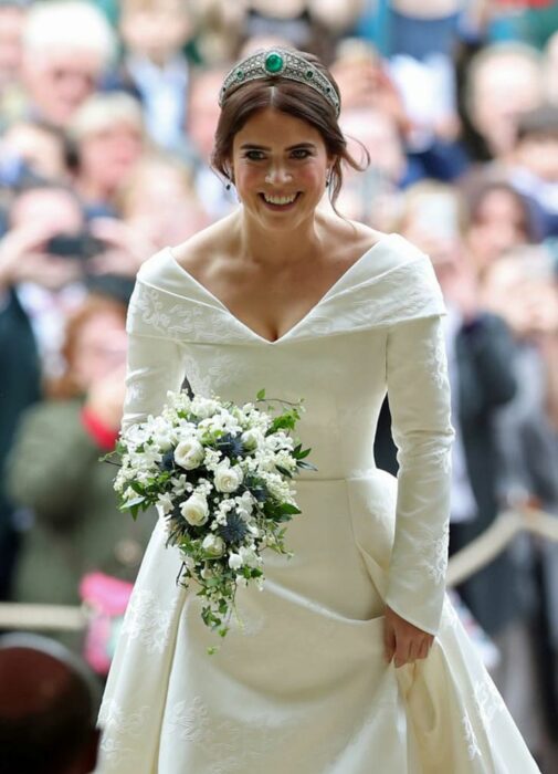 Eugenia de York el día de su boda luciendo un vestido blanco de encaje con un ramo de novia con flores blancas