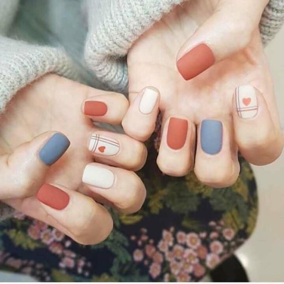 Manicura en tonos rojo ladrillo y azul cielo