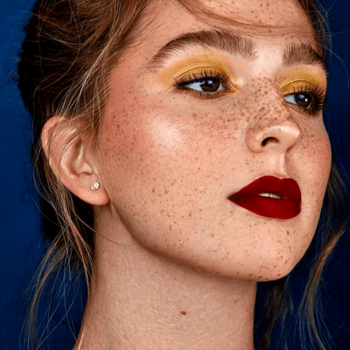 chica rubia con maquillaje de sombras amarillas, lipstick rojo y pecas naturales