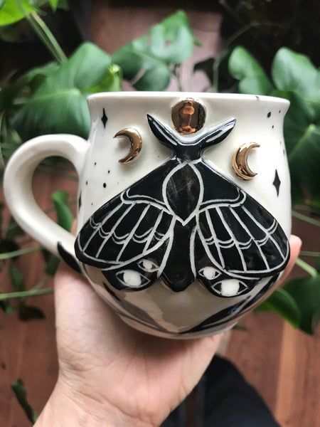 Taza blanca decorada con una polilla negra