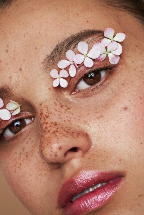 Maquillaje creativo con detalles de flores sobre sus párpados