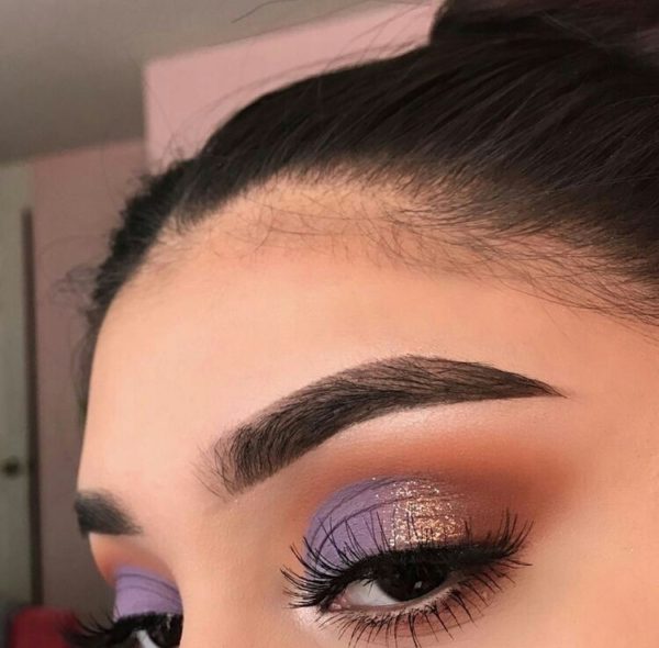 Chica con un maquillaje en tonos morados y dorados brillosos